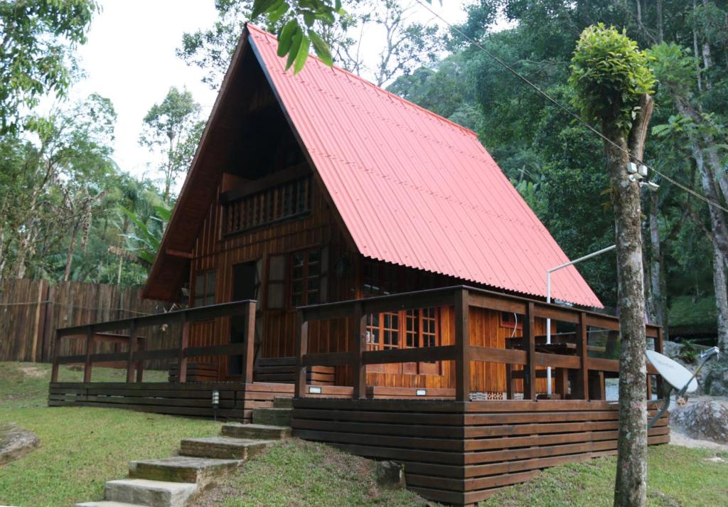 ein kleines Holzgebäude mit rotem Dach in der Unterkunft Cabana da Imperatriz in Santo Amaro da Imperatriz
