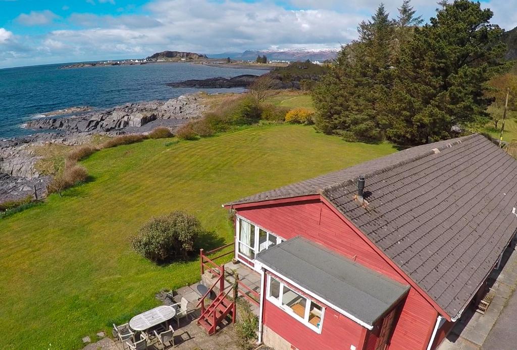 an aerial view of a red house on the ocean at Atlantic Bay Cottage in Clachan