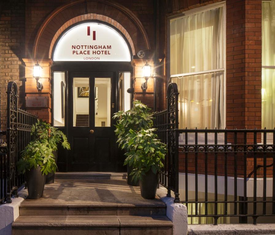 a front door of a building with two potted plants at Nottingham Place Hotel in London
