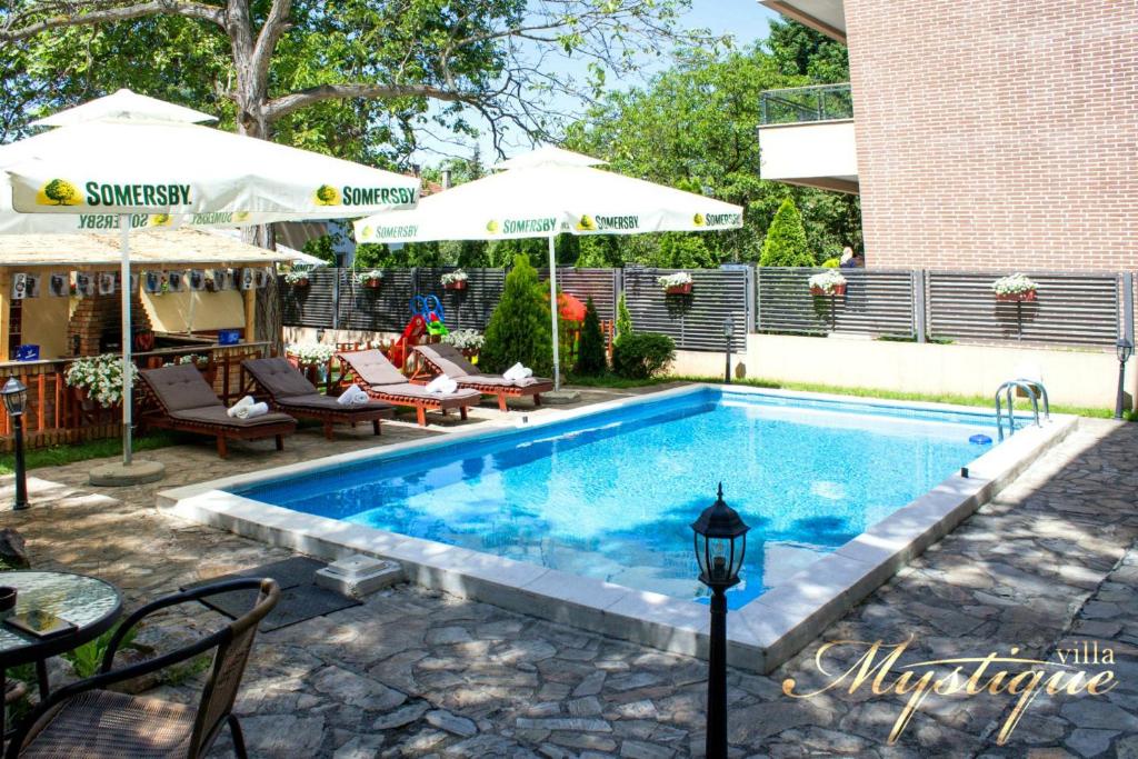 a pool with chairs and umbrellas next to a building at Villa Mystique in Belgrade