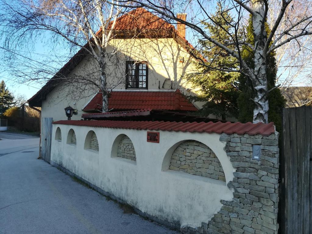 a white building with a brick wall and a fence at Vörös Macska Vendégház in Szentkirályszabadja