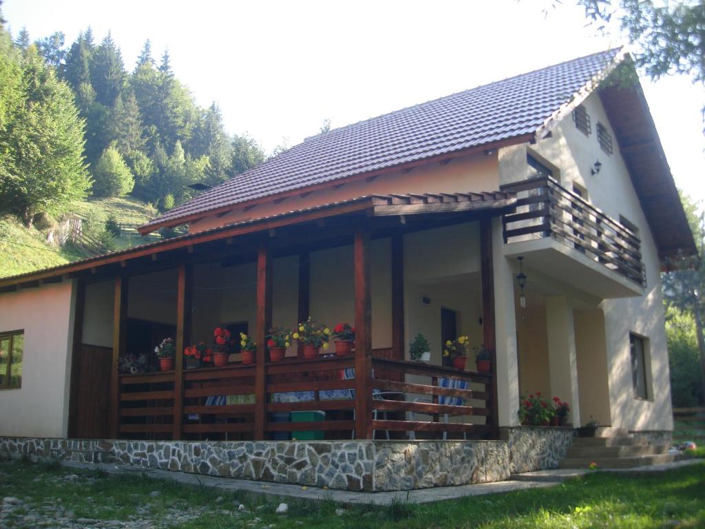 een huis met een veranda met bloemen erop bij Casa Maia Dambovicioara in Dâmbovicioara