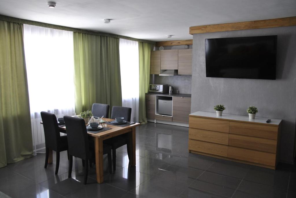 una sala da pranzo con tavolo, sedie e TV di Hotel Albatros a Perm