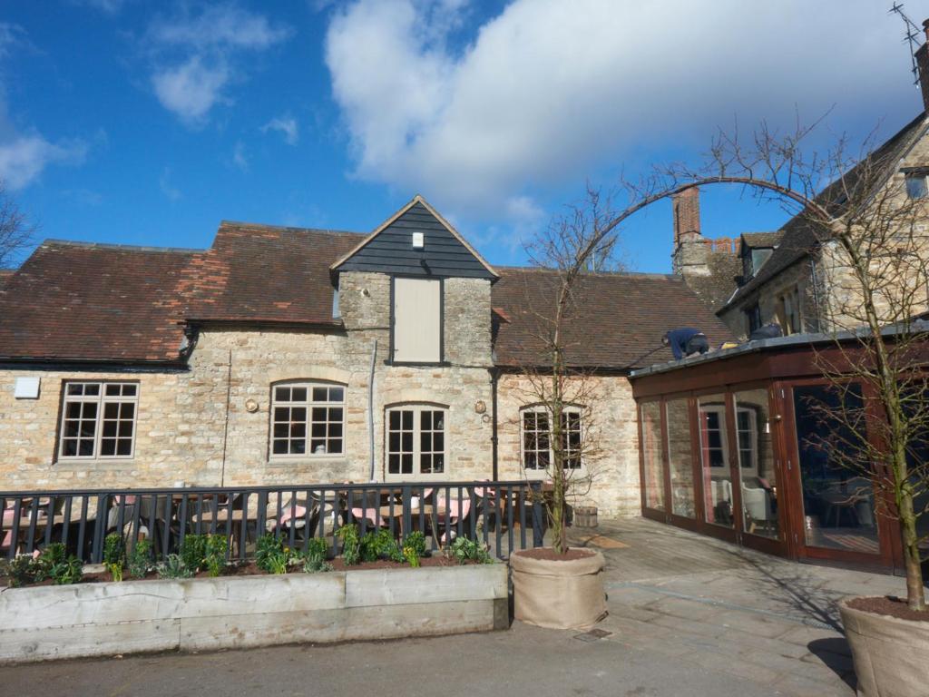 une ancienne maison en pierre avec une clôture devant elle dans l'établissement Bear and Ragged Staff, à Oxford