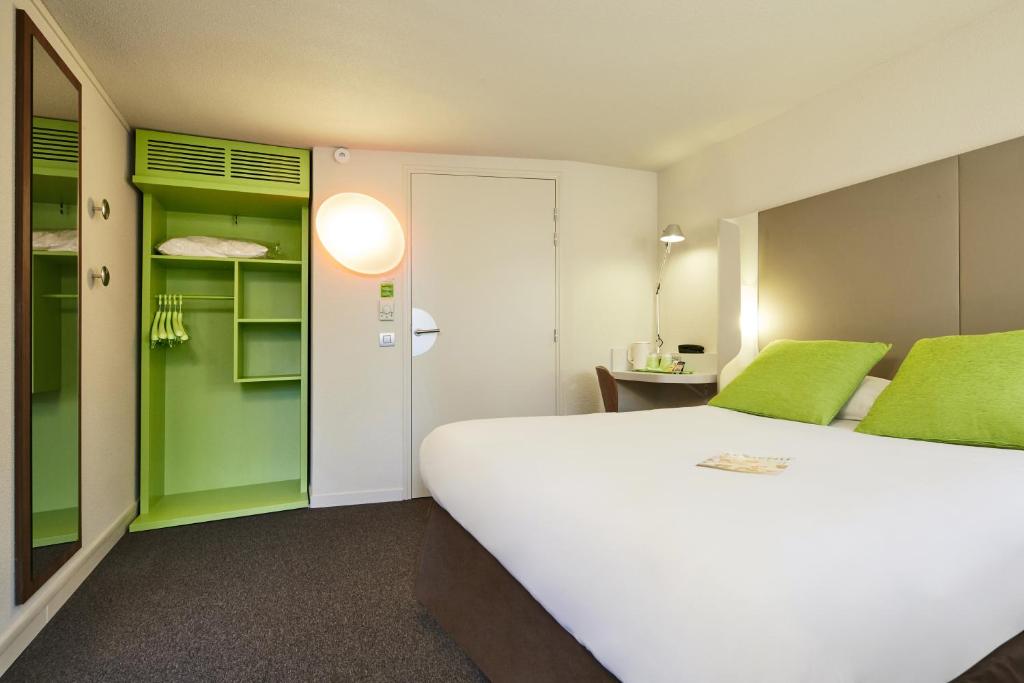 een kamer met een wit bed en een groene kast bij Kyriad Sannois - Ermont in Sannois