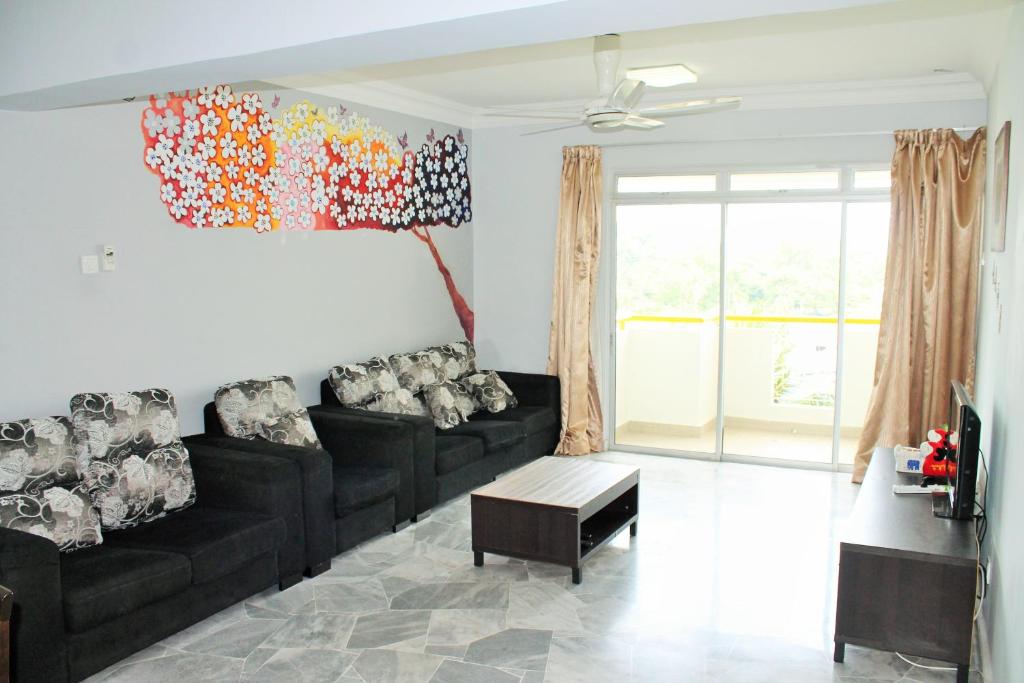 a living room with black furniture and a painting on the wall at Ocean View Resort in Port Dickson