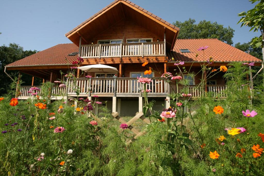 une maison avec une terrasse et un champ de fleurs dans l'établissement Chambre d'hôte L'Arrivée, à Autoire