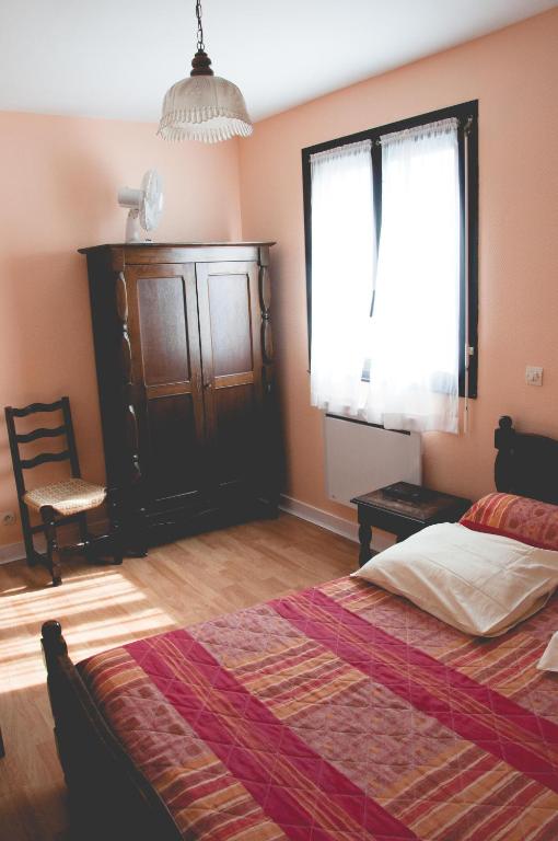 a bedroom with a bed and a chair and a window at Hotel Restaurant Maurice in Châteauroux