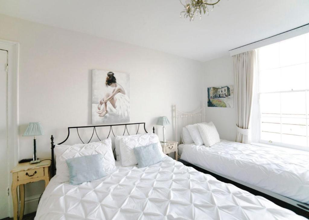 a white bedroom with two beds and a window at No 4 Ainslie's Belvedere B&B in Bath