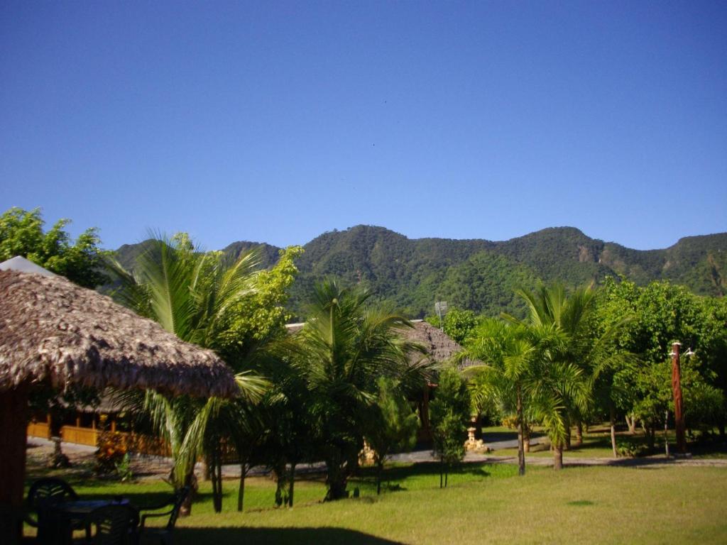 a resort with palm trees and mountains in the background at La Isla de los Tucanes in Rurrenabaque