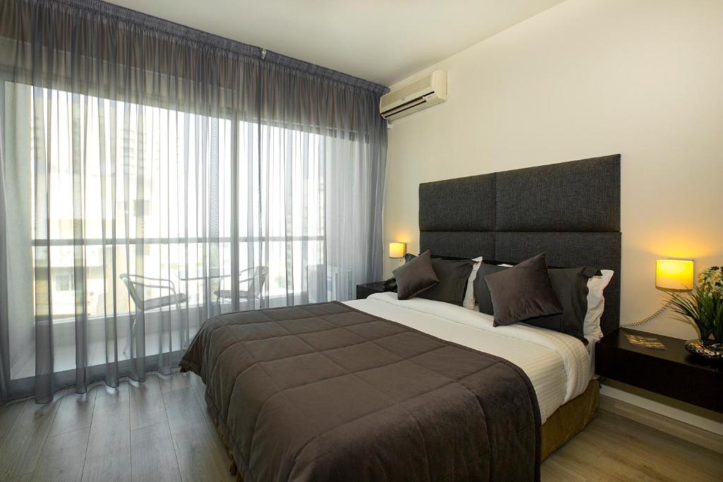 a bedroom with a large bed and a large window at Orient Queen Homes Hotel in Beirut