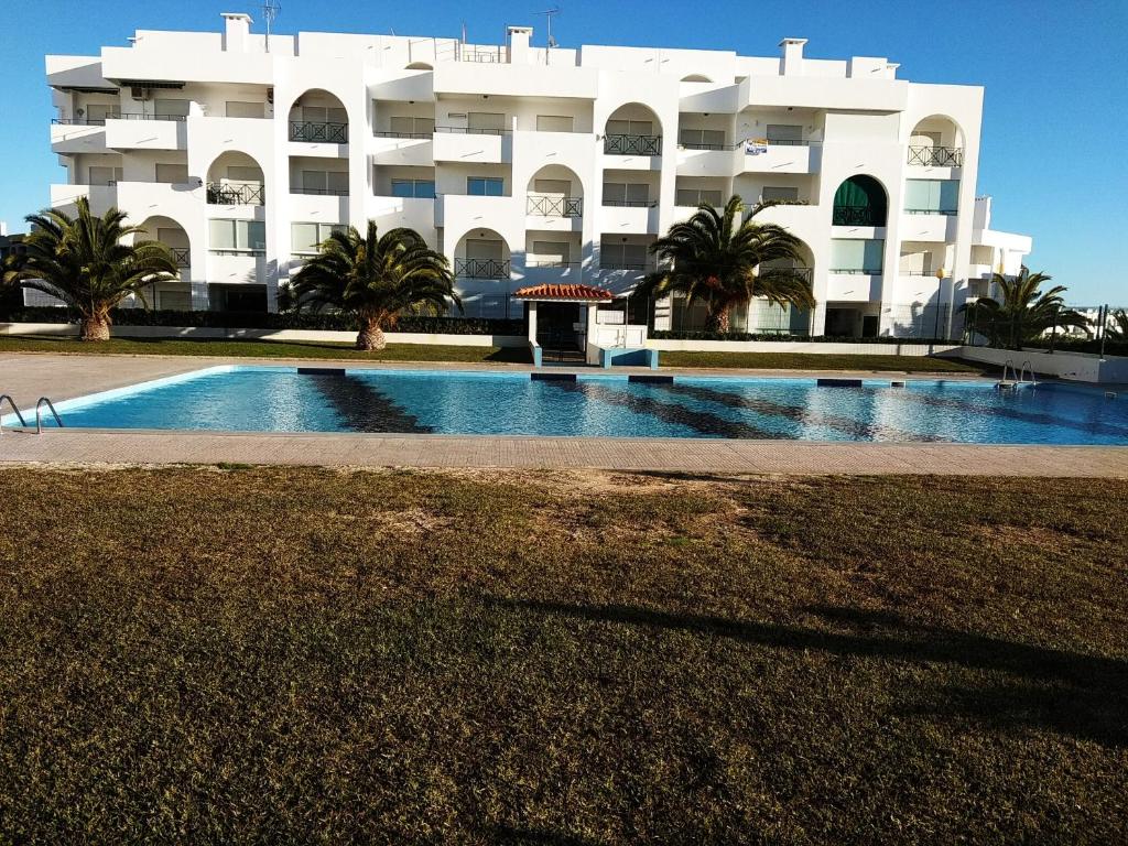 
a large white building with a swimming pool in front of it at Apartamento Varandas do Sol Nascente in Porches
