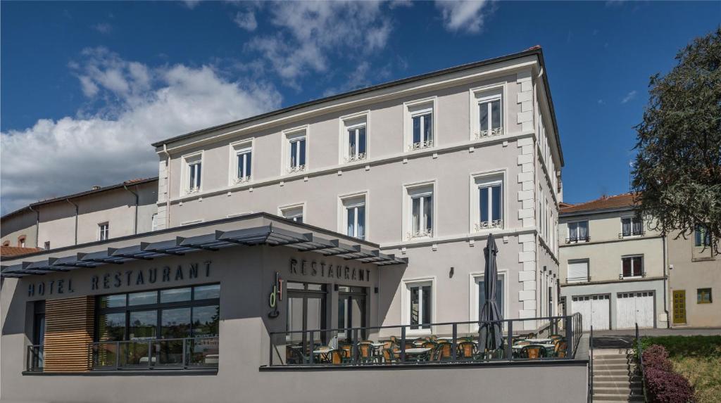 a white building with tables and chairs in front of it at le tisseur des saveurs in Panissières