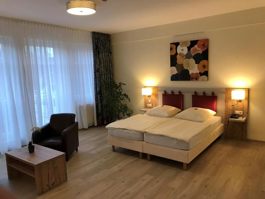 a bedroom with a large bed and a chair at Hotel am Pferdemarkt in Rotenburg an der Wümme