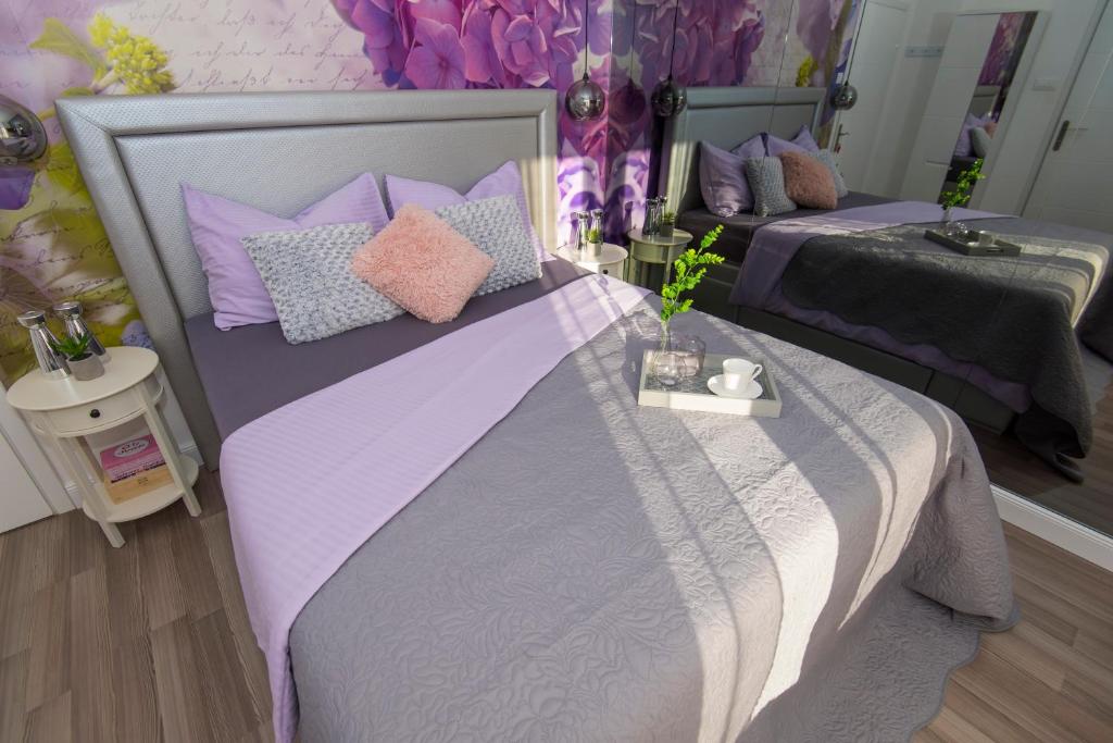 a bedroom with two beds with purple and pink pillows at Guest house Lenny rooms in Zadar