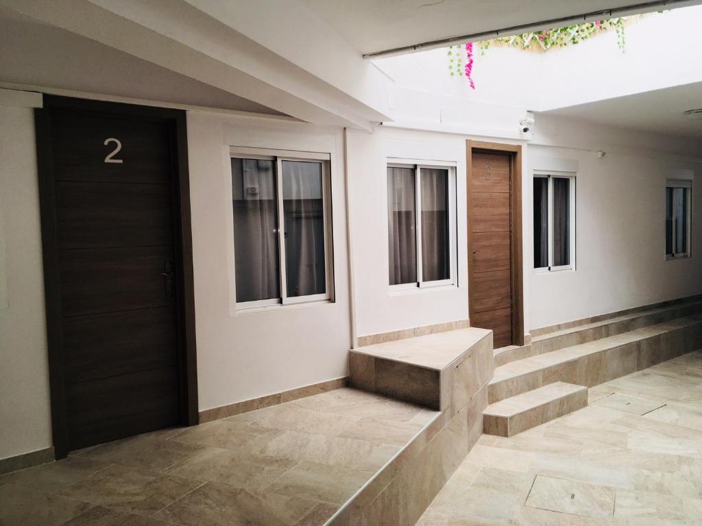 a hallway with stairs and a door and windows at Apartamentos Calypso in Punta Umbría