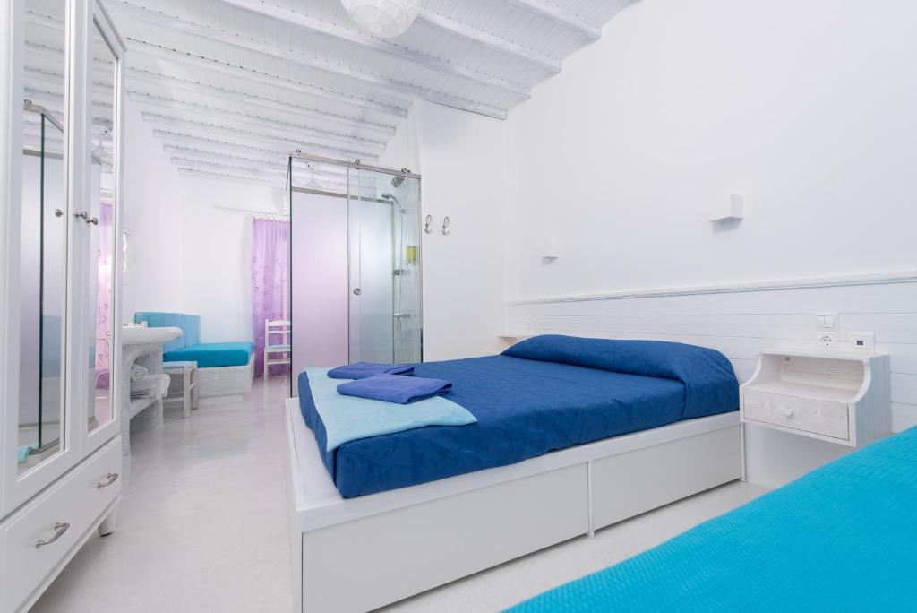 ミコノス・シティにあるMumua Studiosの白いベッドルーム(青いベッド1台、鏡付)
