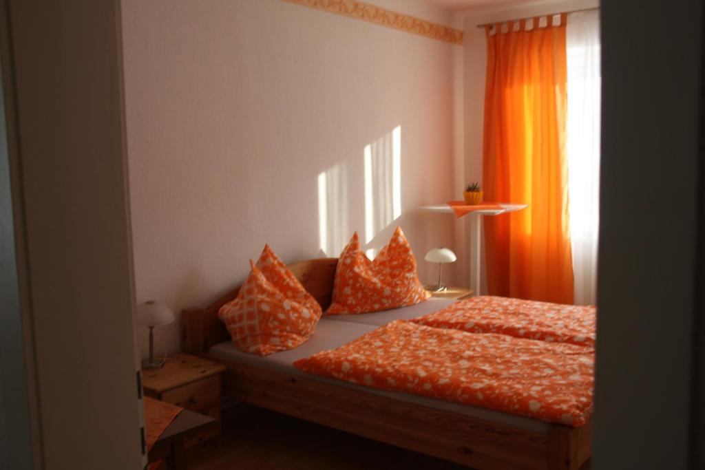 a bedroom with a bed with an orange curtain at Pension Kirchsteiger in Hohenberg