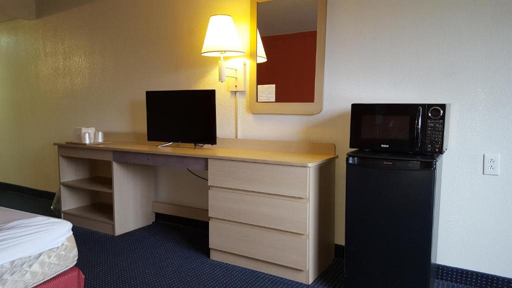 a desk in a hotel room with a microwave at Red Carpet Inn in Gibbstown