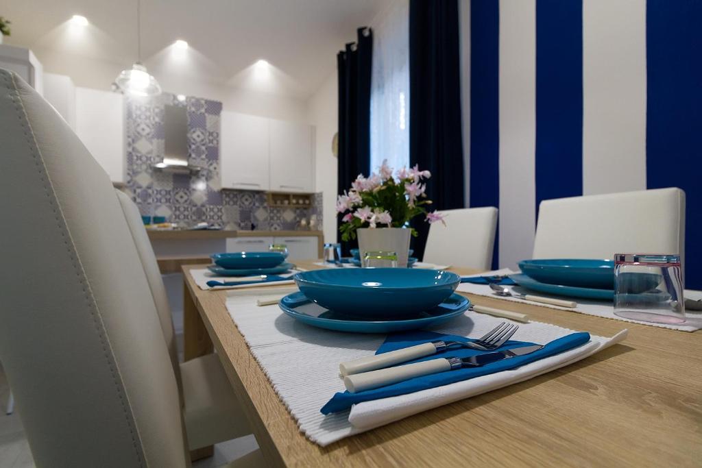 a dining table with blue plates and utensils on it at Kallion house in Vietri sul Mare