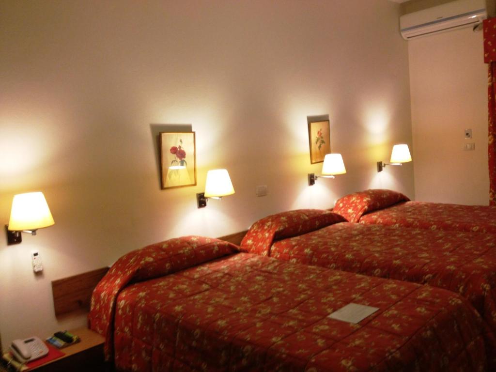 a hotel room with two beds and two lamps at Embassy Hotel in Beirut