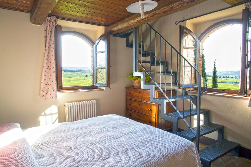 een slaapkamer met een trap, een bed en ramen bij Cinigiano in Cinigiano