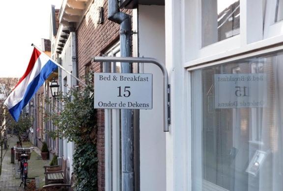 un cartello sul lato di un edificio con una bandiera di Bed & Breakfast Onder de Dekens a Harderwijk