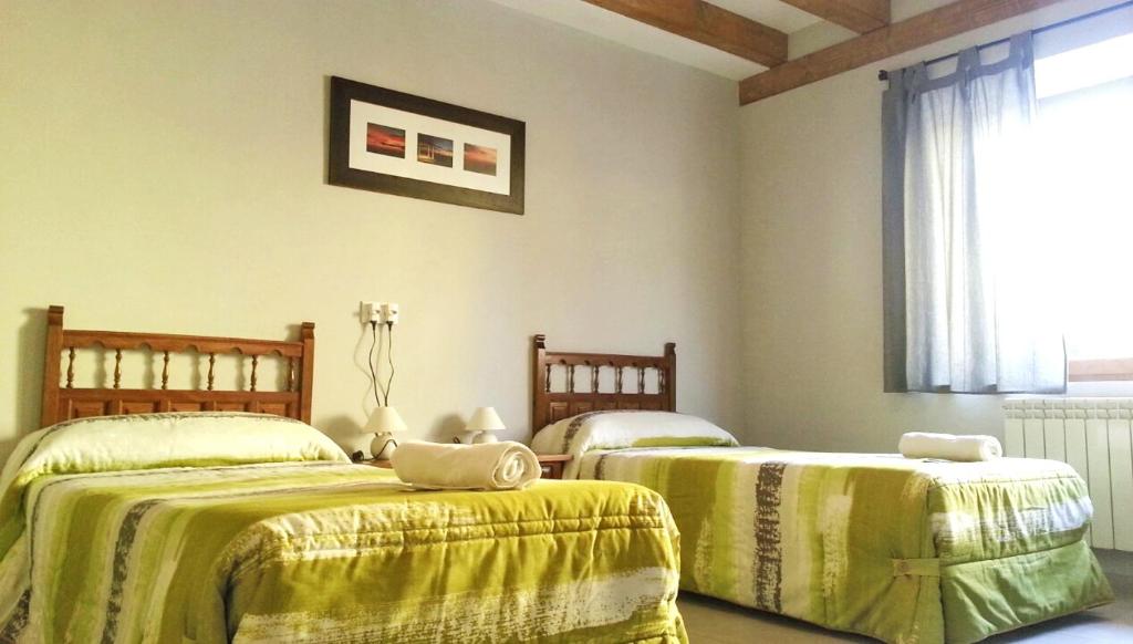 1 Schlafzimmer mit 2 Betten, gelben Decken und einem Fenster in der Unterkunft Albergue Orion in Castrojeriz