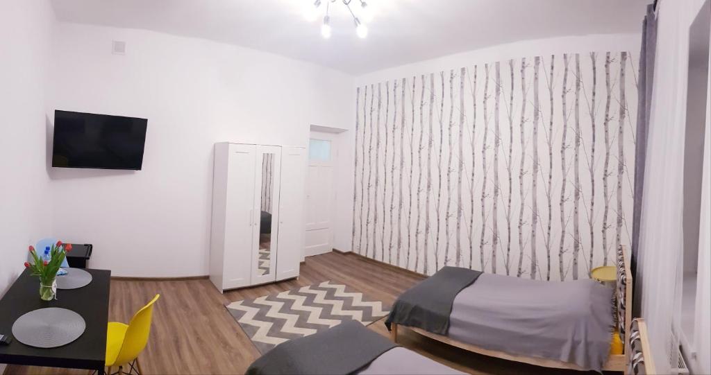 a room with a bed and a table and a tv at Guest Room RÓWNA in Kielce