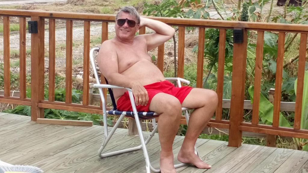 a man sitting in a chair on a deck at The Pool House in Saint Philip
