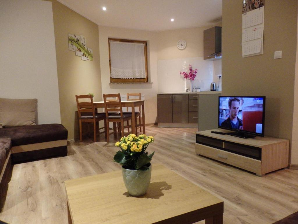 een woonkamer met een flatscreen-tv en een tafel bij Apartament Luna in Karpacz