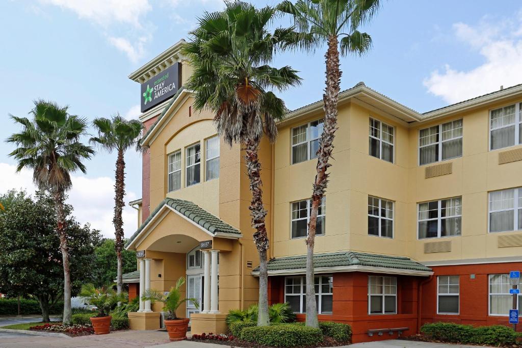 a hotel with palm trees in front of it at Extended Stay America Suites - Orlando - Southpark - Commodity Circle in Orlando