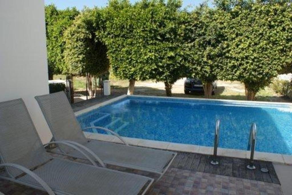 a swimming pool with two lounge chairs next to it at “villa with a pool in a fantastic location” Protaras Villa 49 in Protaras