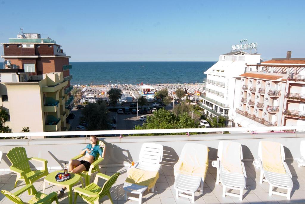 a woman sitting on a balcony with a view of the ocean at Hotel Le Terrazze in Riccione