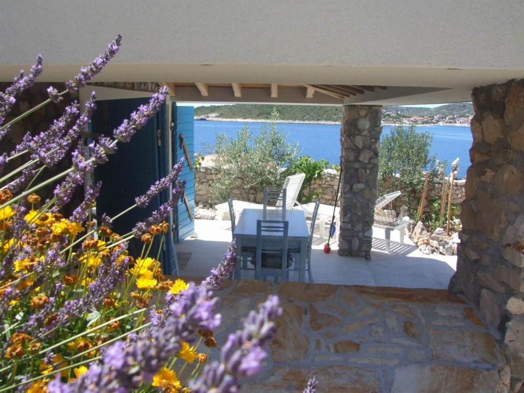 un patio con mesa, sillas y flores en Stone house Marina-SEVID, 1 house-1 apartment, en Sevid