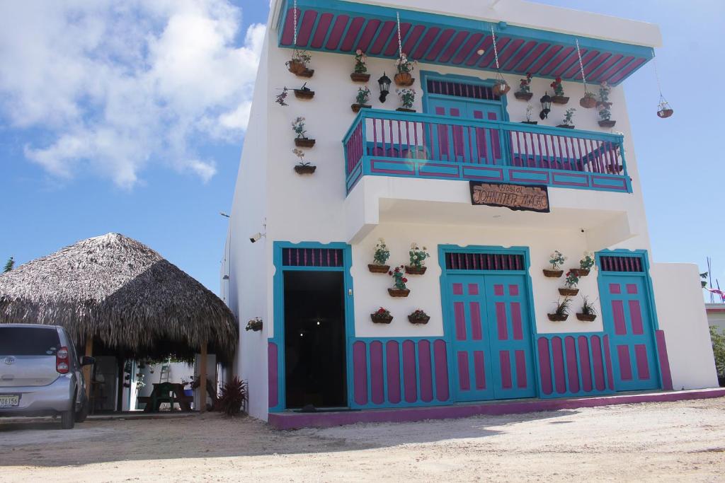 a white building with blue doors and a balcony at Hostal Johnnier Macao Punta Cana in Punta Cana
