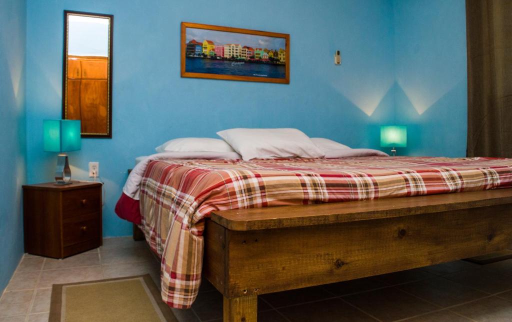 a bedroom with a bed with a blue wall at Nos Krusero Apartments in Sabana Westpunt