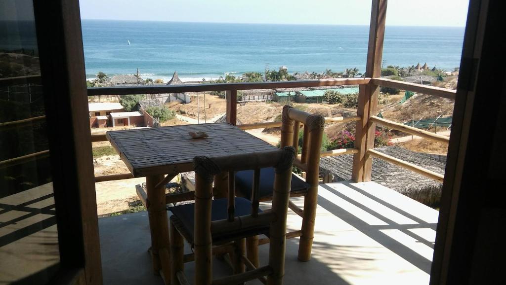 een tafel en stoelen op een balkon met uitzicht op de oceaan bij Altavista Casa de Huespedes in Vichayito