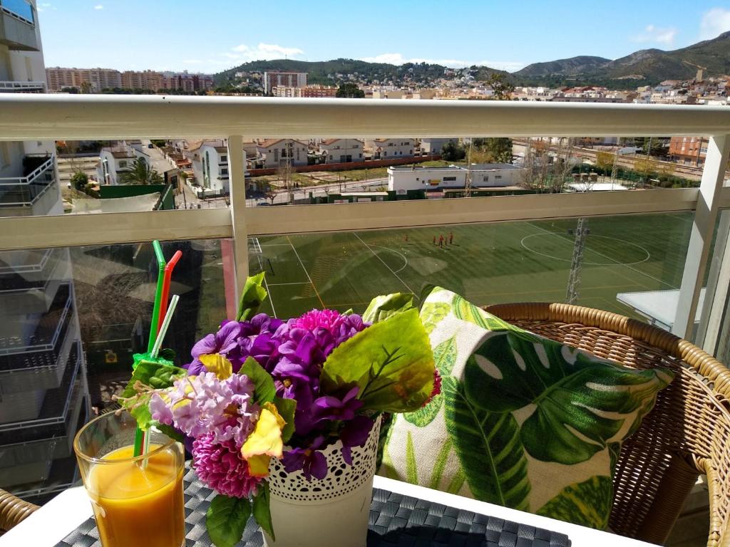 uma mesa com um copo de sumo e flores numa varanda em desolyplaya Colomeras 2J em Oropesa del Mar