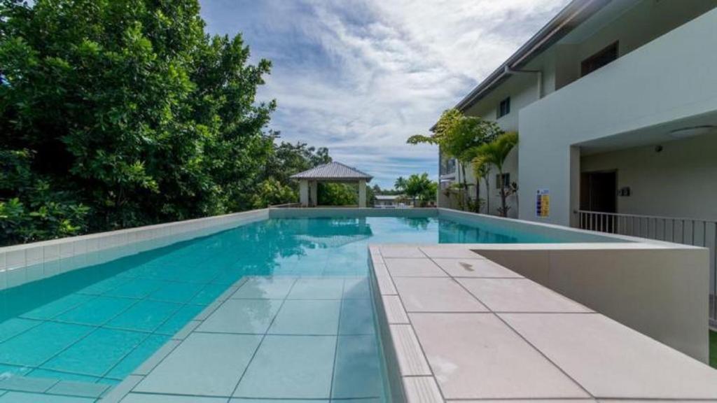 a swimming pool with a gazebo next to a house at Watersons at Airlie Central Apartments in Airlie Beach