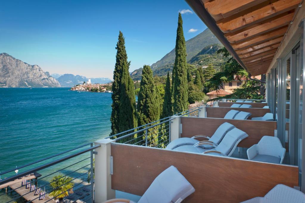 einen Balkon mit Stühlen und Blick auf das Wasser in der Unterkunft Beach Hotel Du Lac Malcesine in Malcesine