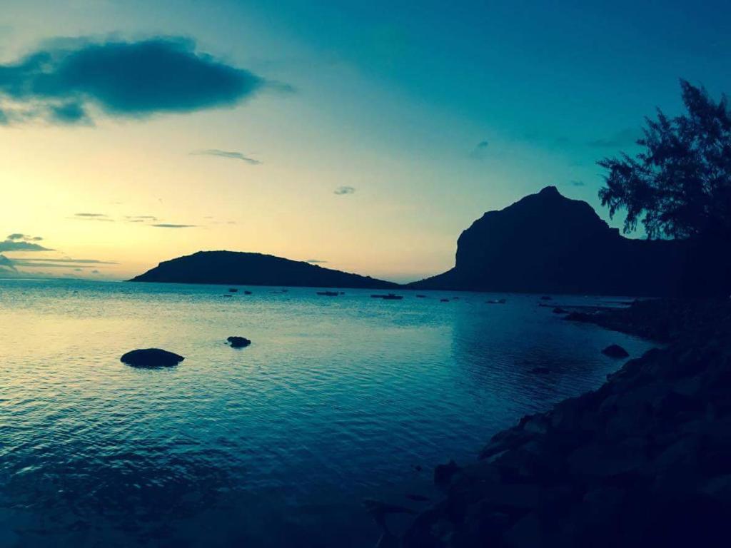 a sunset over a body of water with mountains in the background at Ideal for kite surfer&family in Le Morne