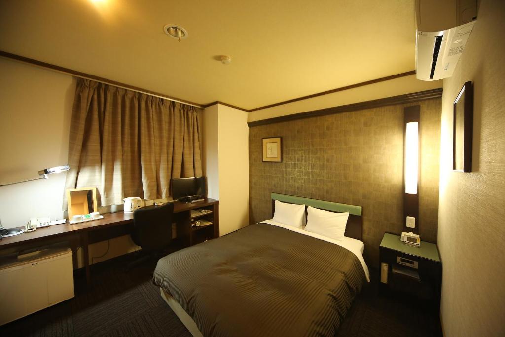a hotel room with a bed and a desk at Hotel Matsumoto Yorozuya in Matsumoto
