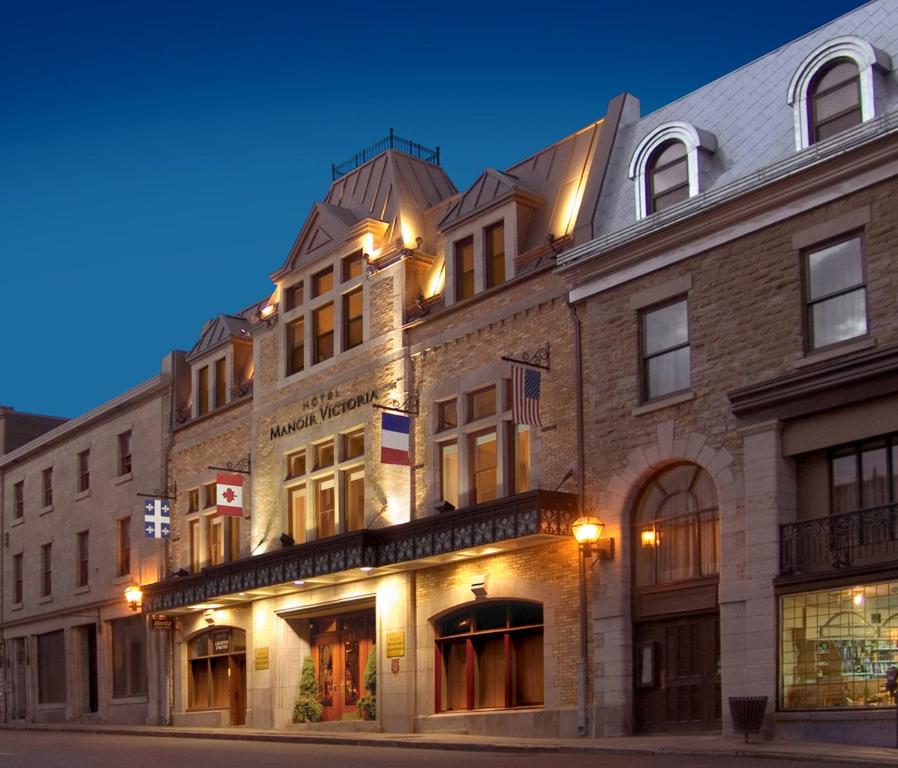 a large brick building on a city street at night at Hotel Manoir Victoria in Quebec City