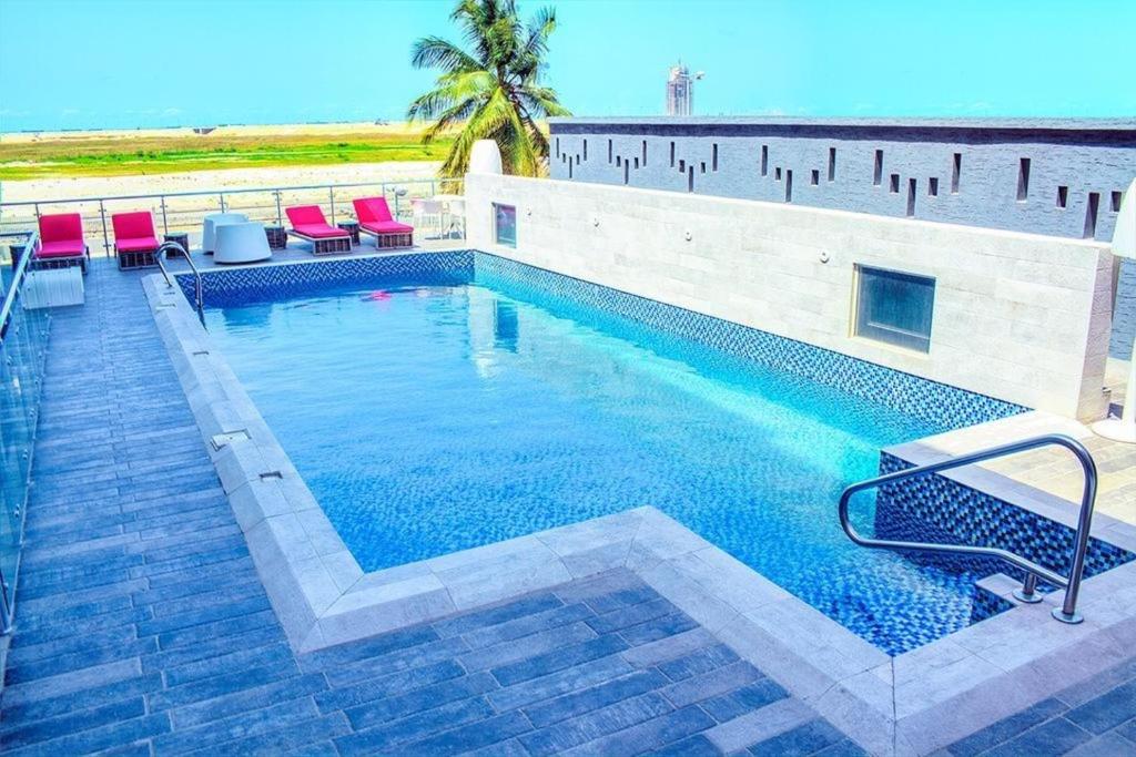a large swimming pool with red chairs and the ocean at BWC Hotel in Lagos