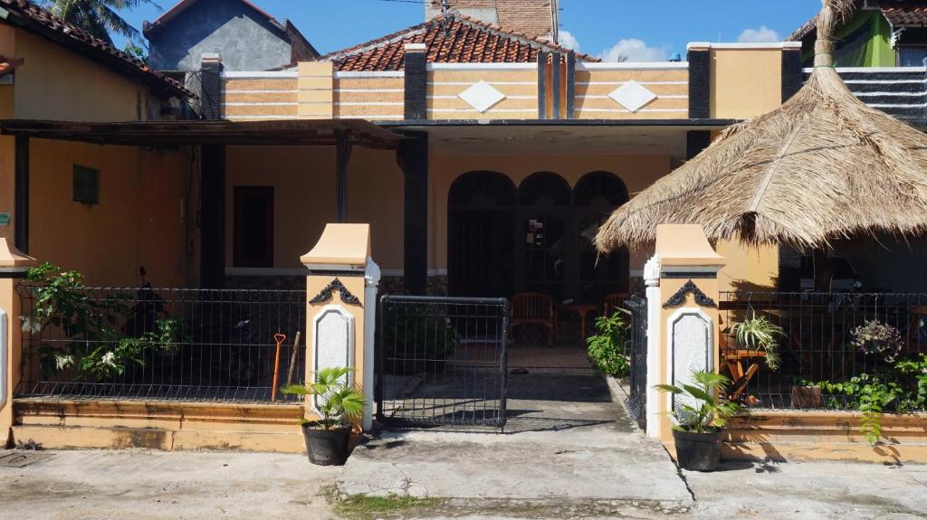 a house with a gate and a thatch roof at Arriani Homestay in Karimunjawa