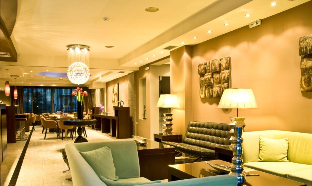 vestíbulo del hotel con sofás, mesa y sillas en Flisvos Hotel Nafpaktos, en Nafpaktos