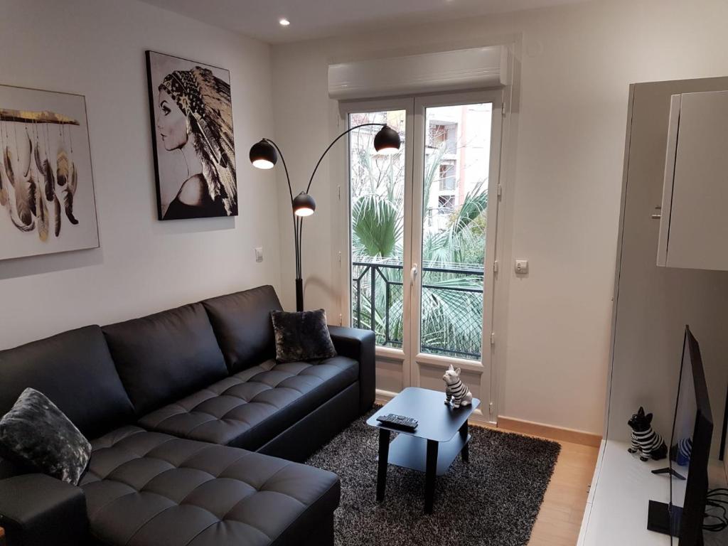 ein Wohnzimmer mit einem schwarzen Sofa und einem Fenster in der Unterkunft Nice Apartment in Menton French Riviera in Menton