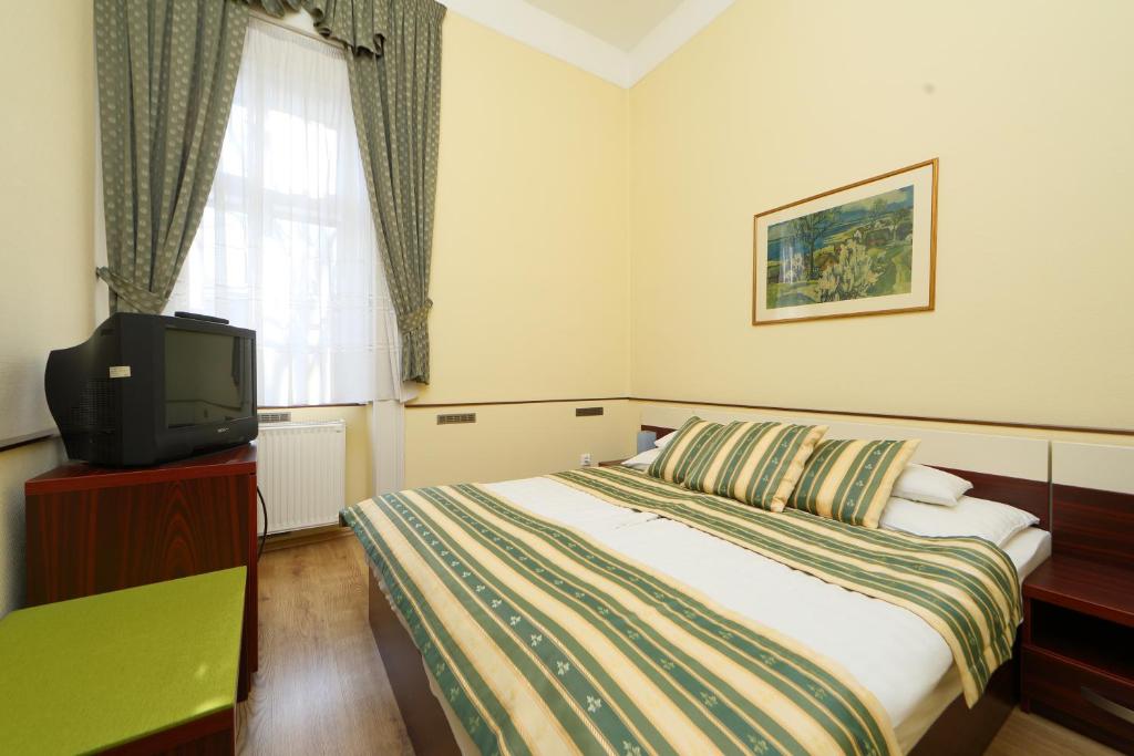 a hotel room with a bed and a tv at Hotel Blaha Lujza in Balatonfüred