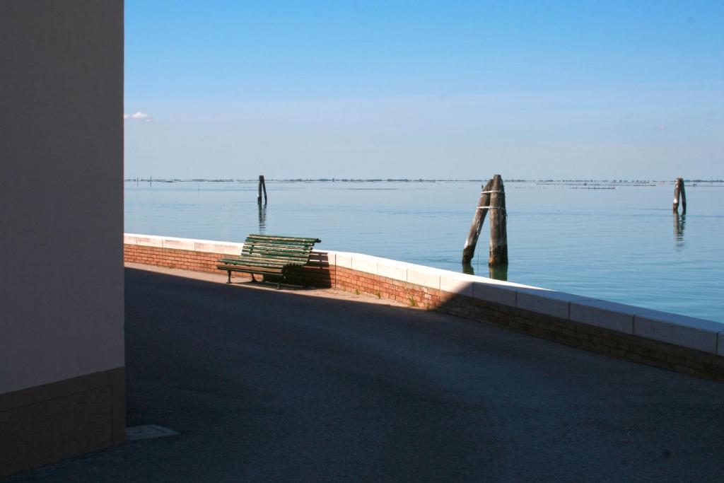 a bench sitting on a wall next to the water at Locanda Stravedo in Pellestrina